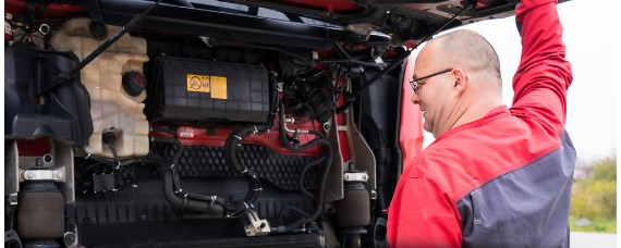 Ein ZEKU-Fahrer prüft bei geöffneter Fahrerhaus-Front den Motorraum der Zugmaschine.