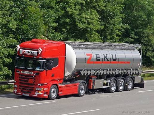 ZEKU-Tankzug in Fahrt: rote Scania-Zugmaschine mit poliertem Edelstahltank, auf dem der Schriftzug ZEKU steht.